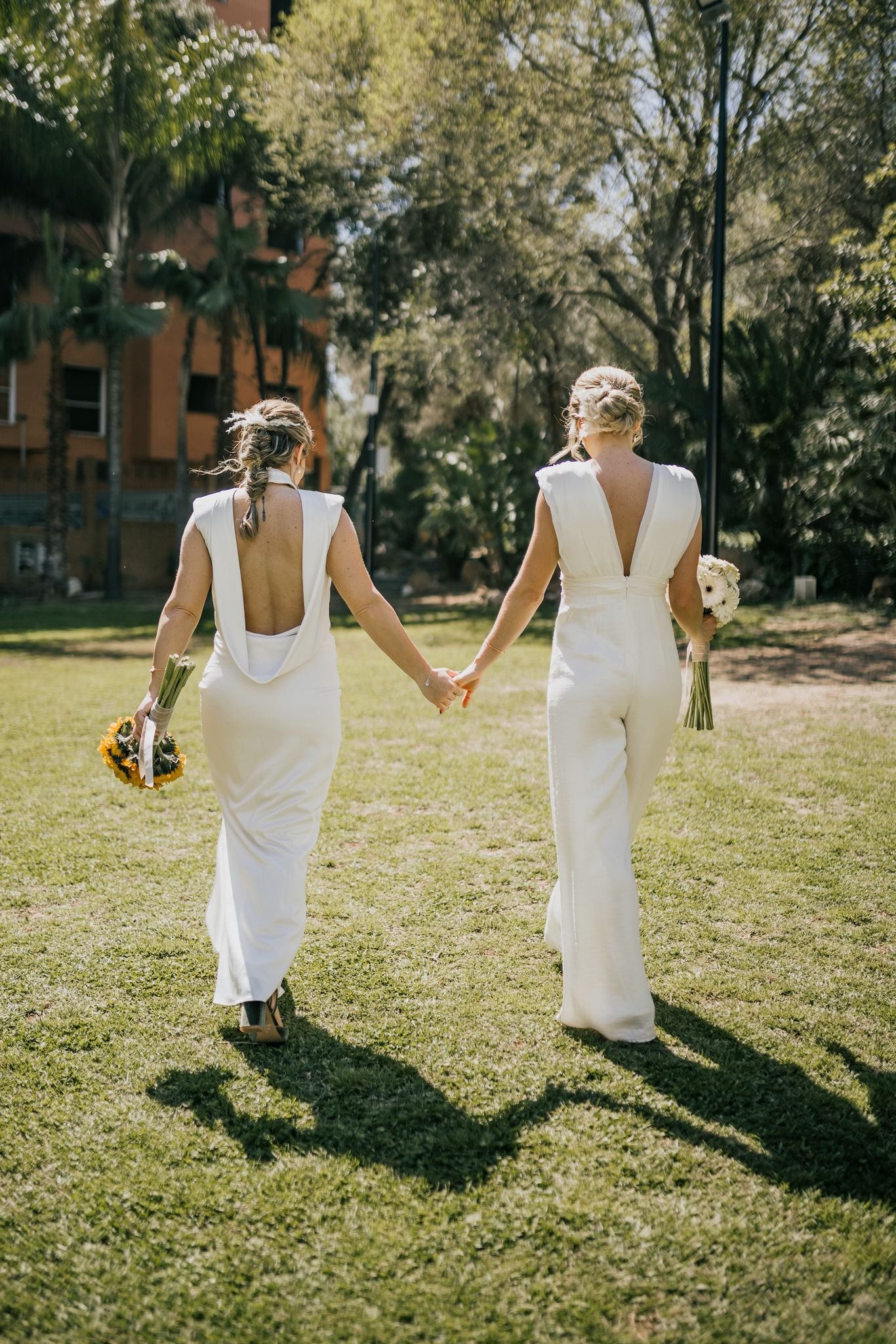 Dos novias caminando de la mano al aire libre